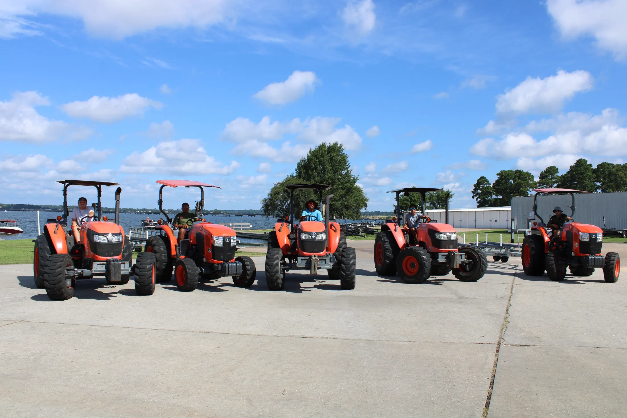 Five valet launch tractors lined up on the ramp at E-Z Boat Storage on Lake Conroe